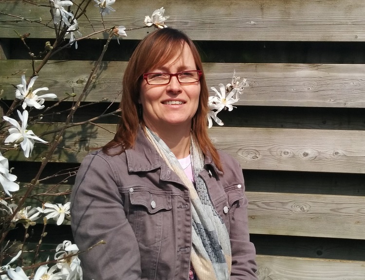 Diane, die door mentale klachten door Leukemie in behandeling is bij het Helen Dowling Instituut, zit tussen de bloemen in haar tuin.
