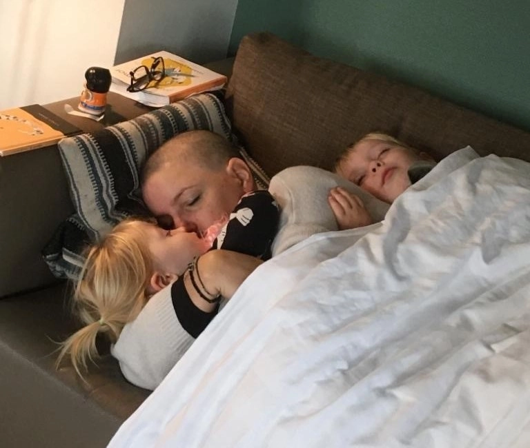 Kirsten Bergkotte ligt, uitgeput door haar chemo en met een kaal hoofd, samen met haar twee jonge kinderen op de bank.